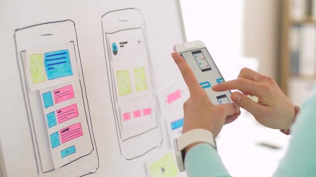 technology and people concept - hands of creative woman or developer working on smartphone user interface design at office