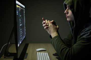 Man wearing hoodie hacking server in dark room. Young man hack server or white hacker protect...