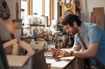 Young woodworker using a tablet in his workshop