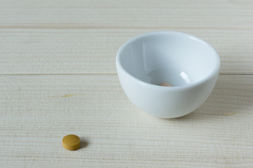 A tablet of medication and drugs in a ceramic cup