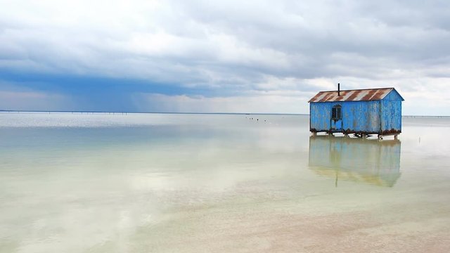 Old Blue House Abandoned in the Middle of the Salt Lake During an Approaching Storm. Salar Saline Salt Salty Lake Dead Sea Baskunchak