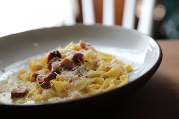spaghetti carbonara white sauce with bacon on wood background in restaurant
