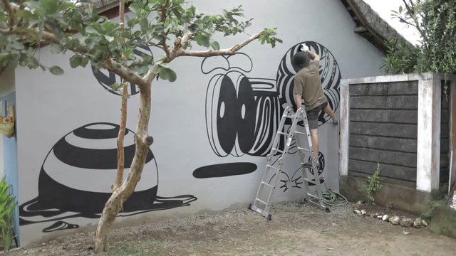 Graffiti artist paint spraying the wall, urban outdoors street art concept