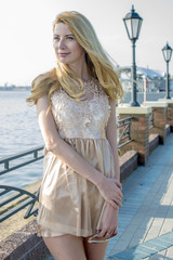 Young beautiful blond woman in a beautiful dress on the waterfront
