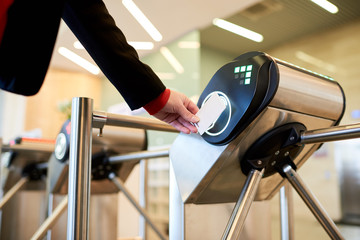 Close up of unrecognizable businesswoman swiping card passing turnstile to enter building