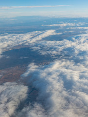 Fototapeta na wymiar Aerial view of the Madrid region, outside the metropolitan area. Flying over agricultural fields and clouds.