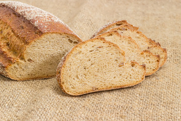 Brown bread with whole sprouted wheat grains on sackcloth closeup