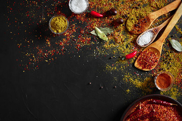 Assorted spices on dark black background. Seasonings for food. Curry, paprika, pepper, cardamom,...