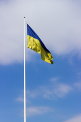 Ukrainian national flag on a flagpole against of sky