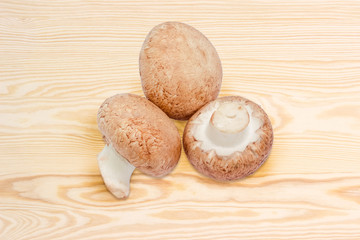 Cultivated raw brown mushrooms on a wooden surface