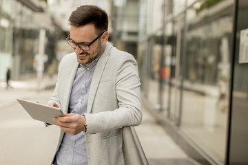 Young businessman with digital tablet by the office building