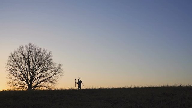 A satisfied farmer dances ib the field. Silhouette of a sunset or sunrise in field.