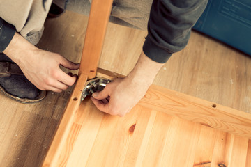 man screws the legs to a wooden table