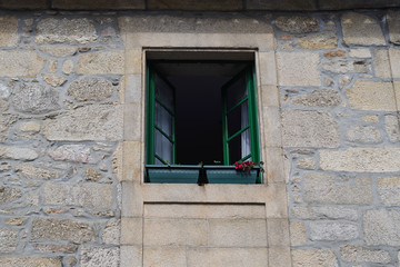 old window with a metal grate in a stone wall