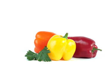 three sweet peppers and a sprig of parsley isolated on white