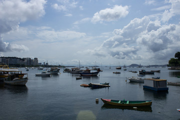 boats and fishing boats parked together on urca beach in rio de janeiro city on sunny day with clouds