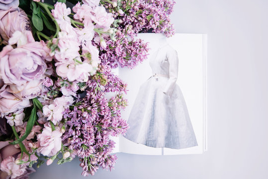 Fototapeta VORONEZH/RUSSIA-02.01.2018: Fashion book depicting old Dior dress with fresh flowers (roses, lilac and mattiolas in lavender color)on the light blue background