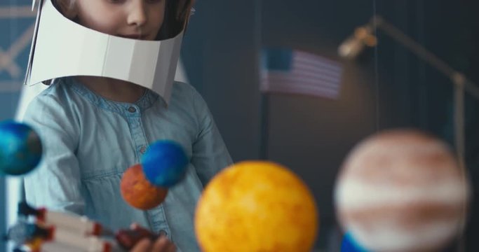 CU Cute little girl wearing cardboard astronaut helmet flying toy rocket with attached red sports roadster car to it. 4K UHD 60 FPS SLOW MO
