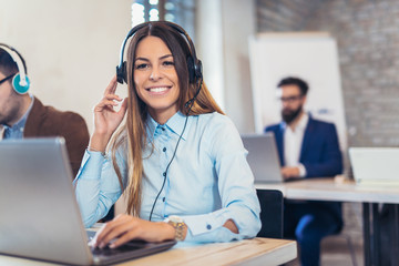 Portrait of happy smiling female customer support phone operator at workplace.