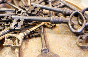 A bunch of antique keys on a metal tray