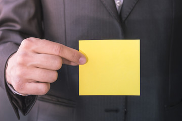 Blank paper card for text. Copy space. Business man in suit, holding in hand yellow sheet