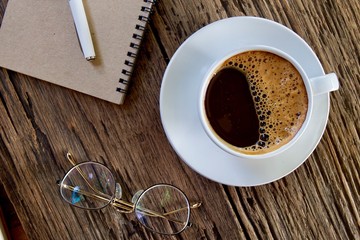 Coffee cup hot and notebook pen on wooden table