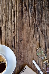 Coffee cup hot and notebook pen on wooden table