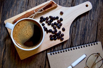 Coffee cup hot and notebook pen on wooden table 