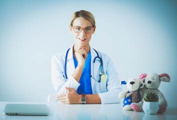 Beautiful young smiling female doctor sitting at the desk.