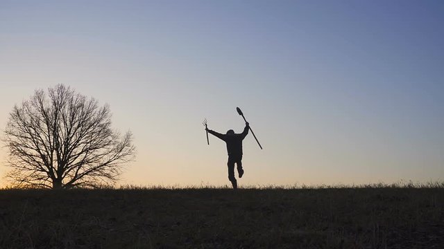 A satisfied farmer dances ib the field. Silhouette of a sunset or sunrise in field.