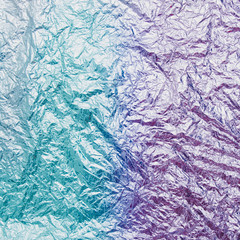 the holographic metal foil with a gradient of bright green and blue colors. fashion texture
