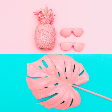 pink sunglasses, pineapple and tropical palm leaves of monstera on dual color background. fashion creative concept. minimal and surrealism, flat lay, top view