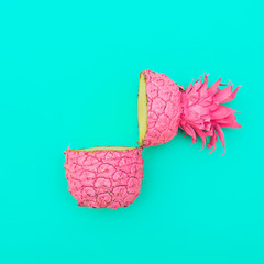 two painted in pink color halfs of the pineapple on turquoise background. minimalism and surrealism of food. flat lay