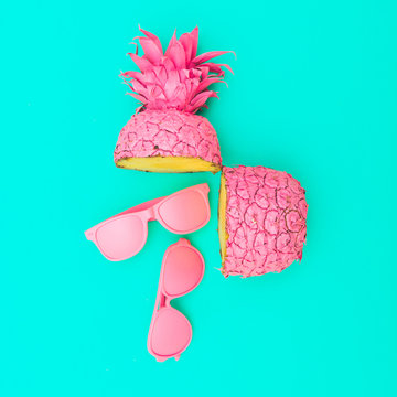 two painted in pink color halfs of the pineapple of which fall sunglasses. fashion minimalism concept. surreal