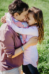 Fototapeta premium Happy mother and daughter holding each other nose to nose and smiling outside on shiny day. Happy Mother's Day. Mom of a daughter, happy family with small children.