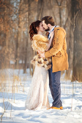 The bride and groom kiss in the sunny winter park. Winter wedding.