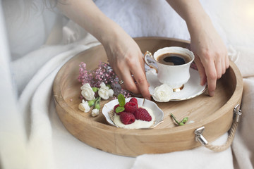 Obraz na płótnie Canvas Fragrant coffee in female hands. Breakfast in bed. Romance. White and pink flowers. light colors. Food and coffee on the tray