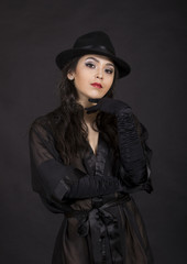 Beautiful young girl in black tunic, black gloves and black hat.