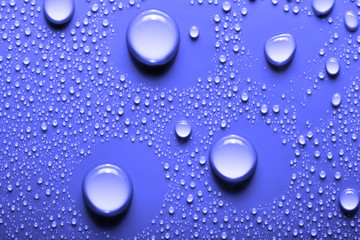 Small and large drops of water on a colored background. Abstract liquid sprays