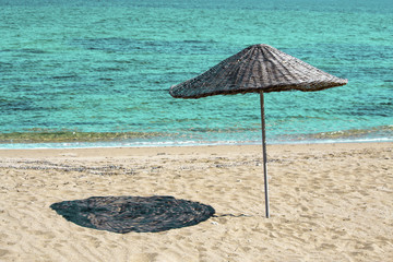 Braided straw umbrella on sandy beach