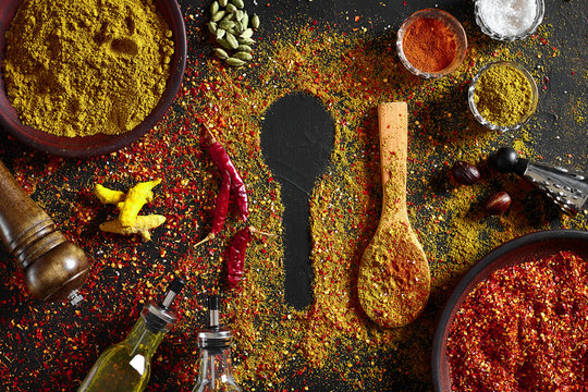 Assorted spices on dark black background. Seasonings for food. Curry, paprika, pepper, cardamom, turmeric. Top view.