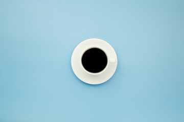 Black coffee in white cup on blue blackground pastel style copyspace flatlay.