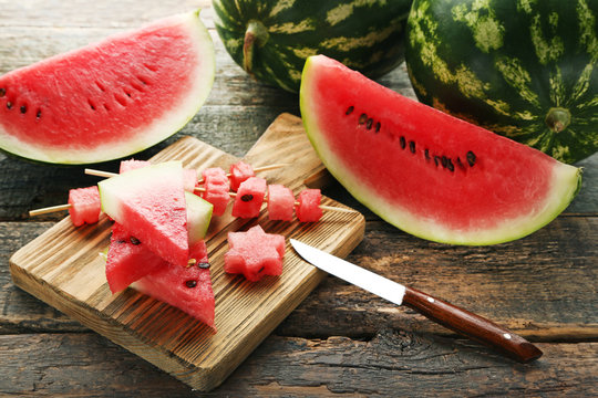 Slices of watermelons with cutting board and knife on grey wooden table