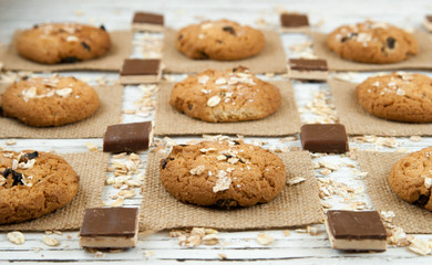Oatmeal cookies and chocolate pieces on a white vintage table.