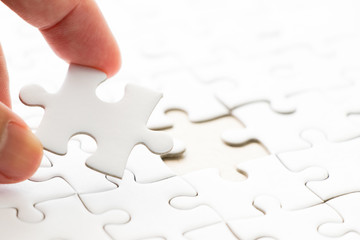 Closed up background of white plain jigsaw with hand that hold missing piece to match or fulfill