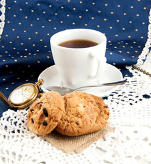 Tea cup. cookies and clock on a wooden white textured table, vintage style.Vintage photography.