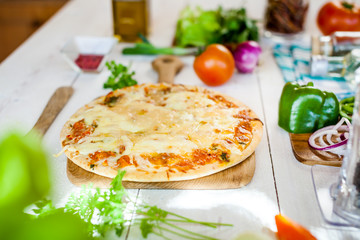 closeup fresh homemade traditional cheese italian pizza on wooden table with ingredients around. wallpaper for pizzeria and cooking food concept