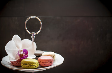 Tender pink and cream macarons and flower on black stone background. soft focus
