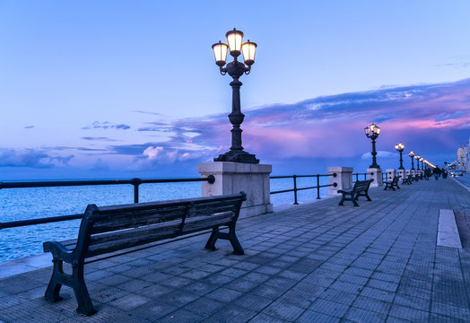 Bari seafront at sunset Purple and blue sky landscape panorama. Bench and street lamp near the sea