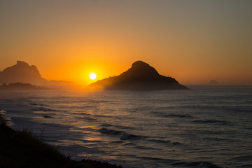 Fototapeta na wymiar color photography of sunrise between mountain on macumba beach in rio de janeiro city